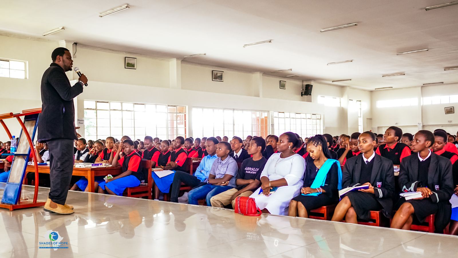 A SOHA mentor speaking to a hall full of students