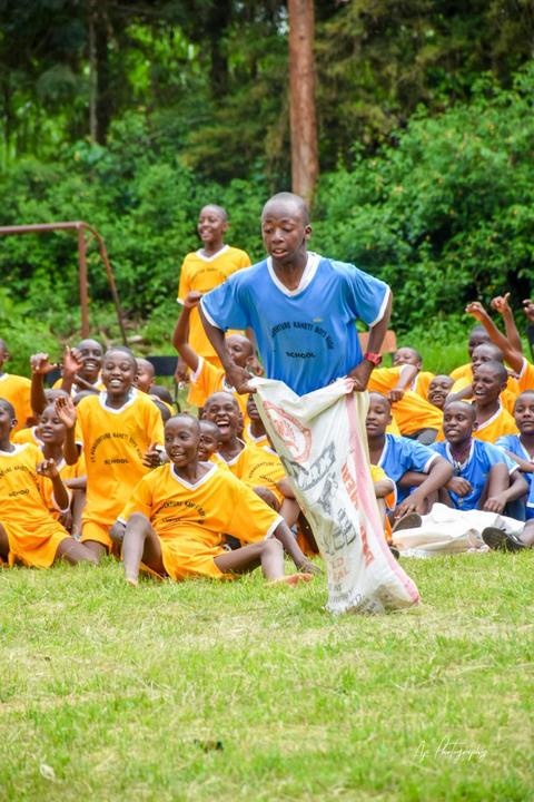 A student hopping in a sack race while classmates cheer