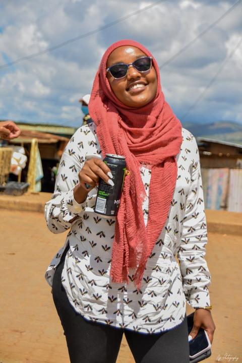 A young woman in a headscarf and sunglasses smiling